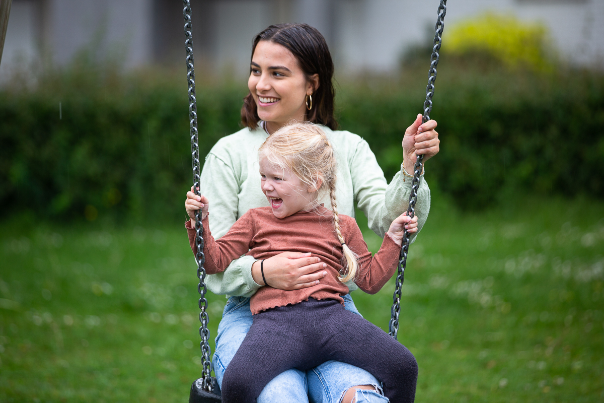 Jonge vrouw met kind op schommel